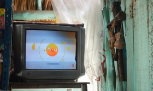 CANCÚN, QUINTANA ROO, 09DICIEMBRE2015.-La señora Maria Elena Tziu originaria de Peto Yucatan observa su televisiòn analógica en su tienda mientras espera que sus 10 hijos le regalen una nueva televisiòn digital. Por otra parte la familia Arce disfruta ya de su television digital otorgada por el Gobierno Federal. FOTO: ELIZABETH RUIZ /CUARTOSCURO.COM